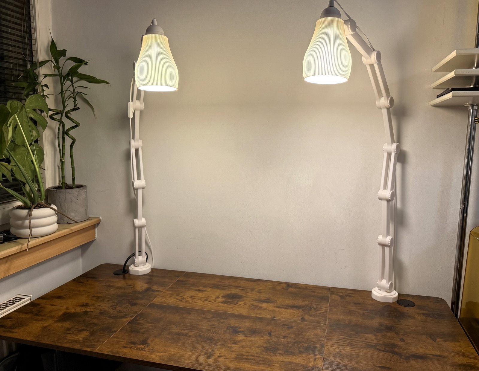 Two 3D-printed DeskLamps clamped to a desk, glowing warm